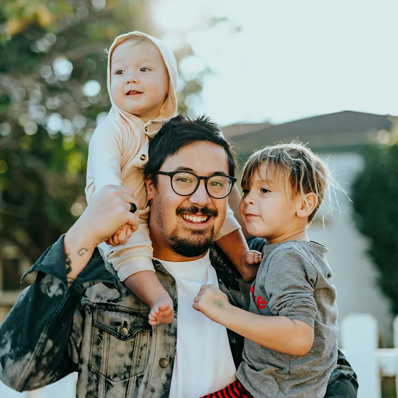 man in white shirt carrying two kids